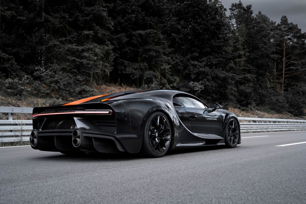 Das Heck des schwarzen Prototypen Bugatti Chiron Super Sport 300, der auf einer asphaltierten Teststrecke vor einem Wald steht.
