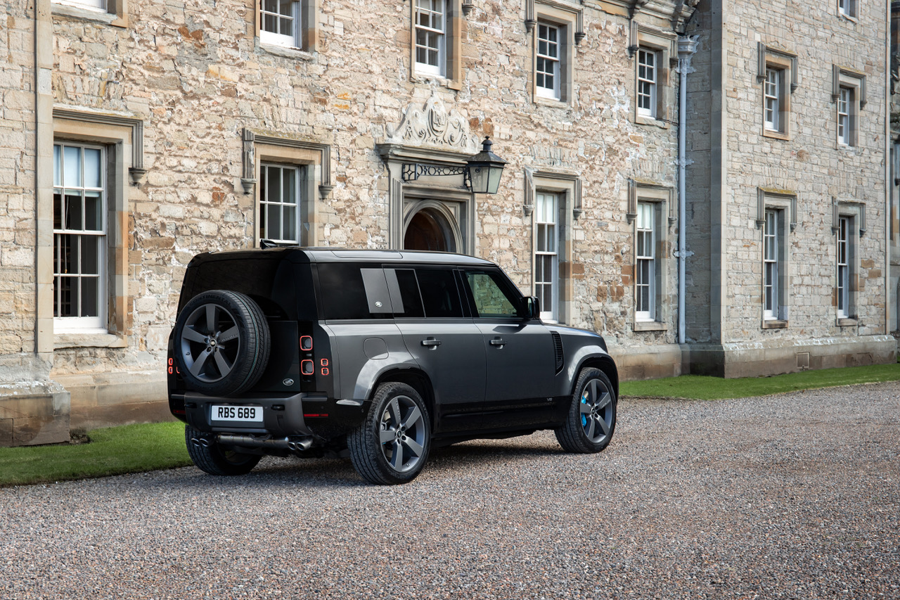 Ein dunkler Land Rover Defender steht vor einem Steinhaus. 