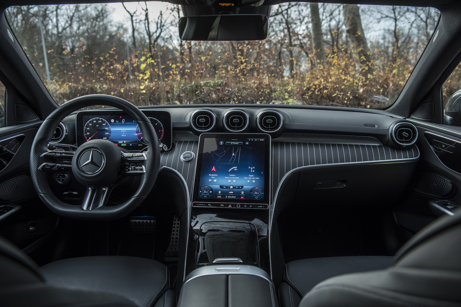 Der schwarz gehaltene Innenraum einer neuen Mercedes C-Klasse mit großem Touchscreen in der Mitte.
