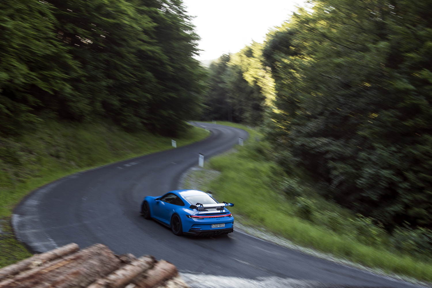 Ein blauer Porsche 911 GT3 fährt durch eine Kurve im Wald.