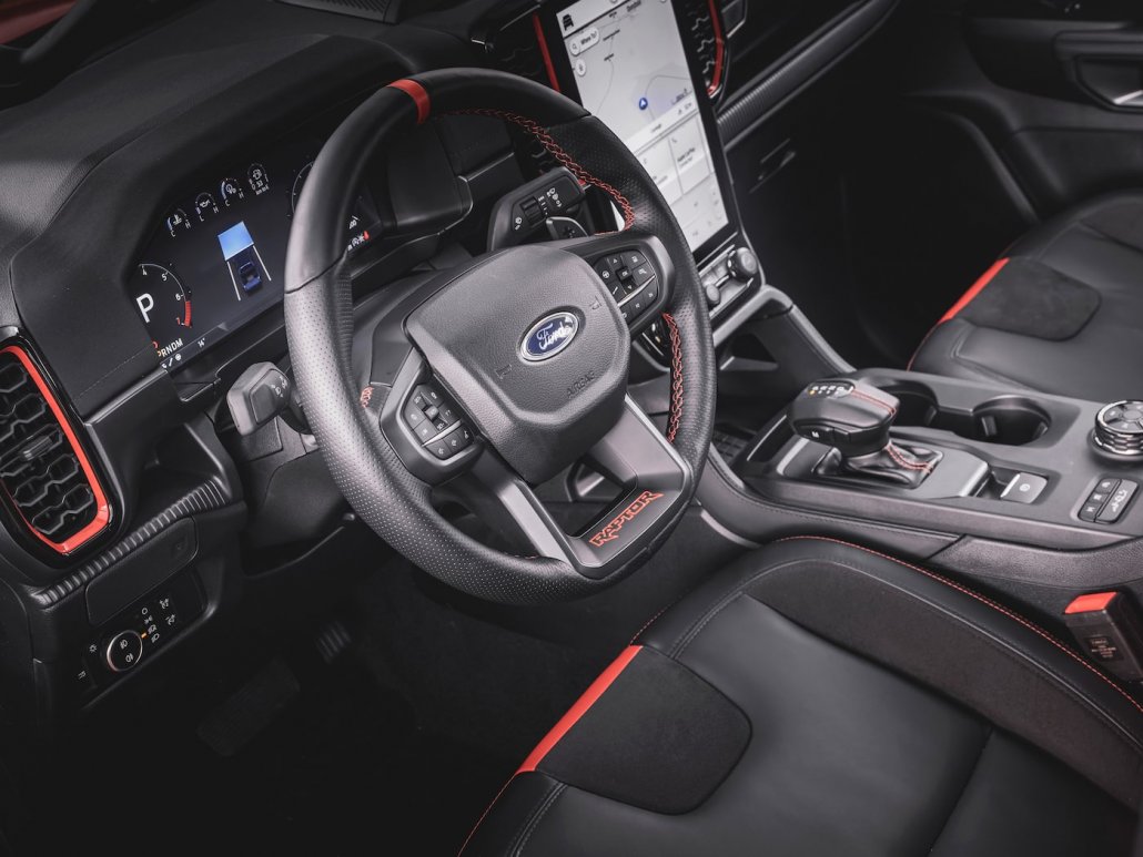 Das großteils schwarzene Interieur eines Ford Ranger Rapter 2022 mit orangenen Akzentfarben und Kontrastnähten.
