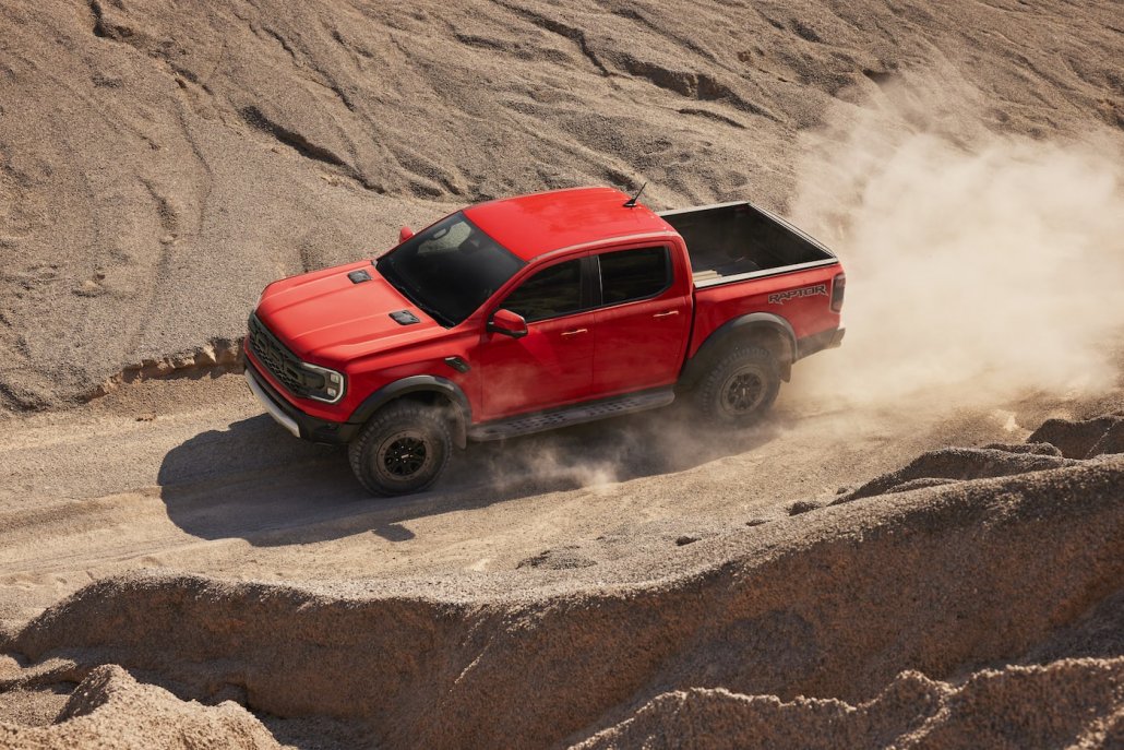 Ein orangener Ford Ranger Raptor 2022 fährt durch eine kleine Schlucht in der Wüste.
