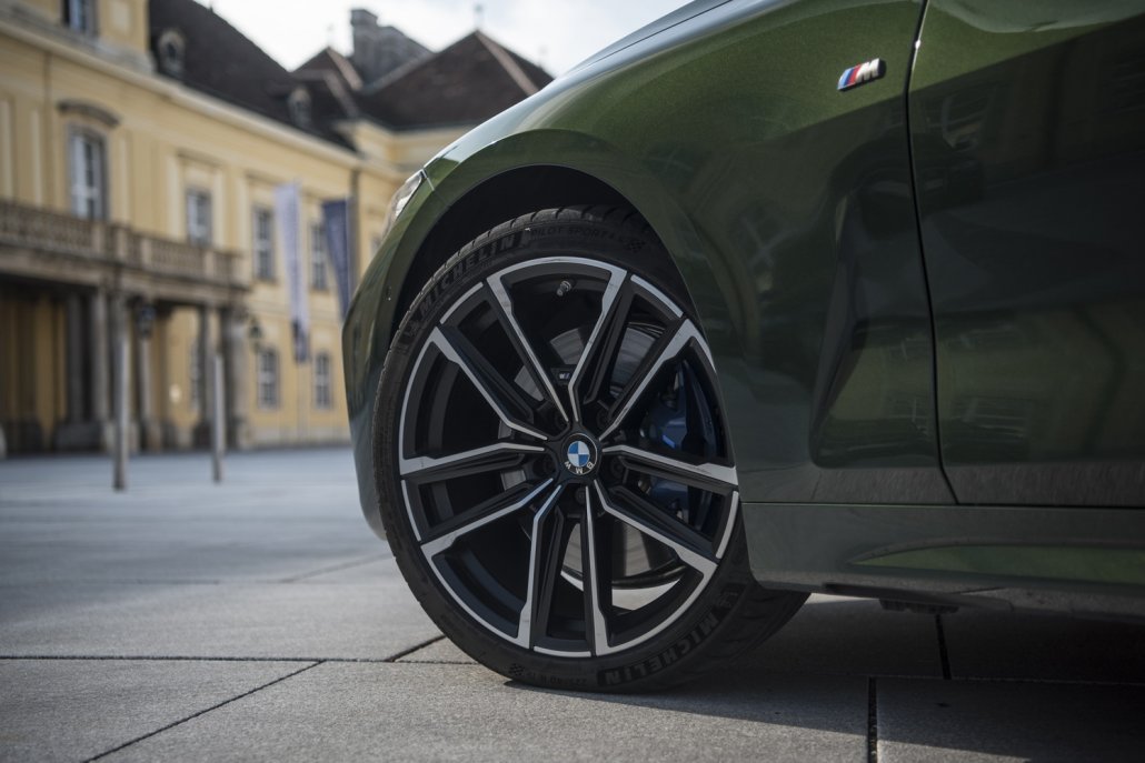 Die schwarz-graue Felgen des linken Vorderrades eines grünen BMW 4er Cabrios.