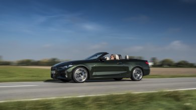 Ein grünes BMW 4er Cabrio fährt auf einer Landstraße an einem schönen Tag.