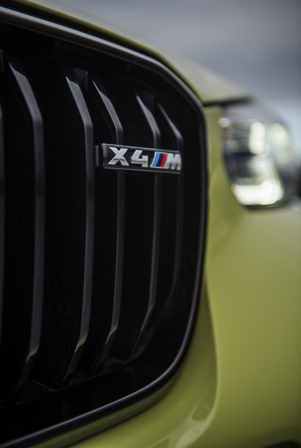 Der chrom-farbene X4 M Schriftzug am Kühlergrill eines BMW X4 M Competition.