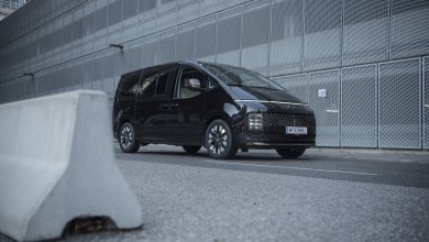 Ein schwarzer Hyundai Staria steht auf Asphalt vor einem grauen Parkhaus