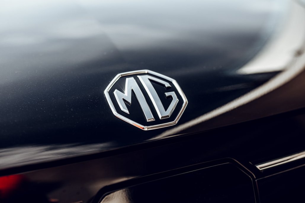 Eine Detailaufnahme des chomenen MG-Logos auf der Motorhaube eines schwarzen MG5 Electrics.