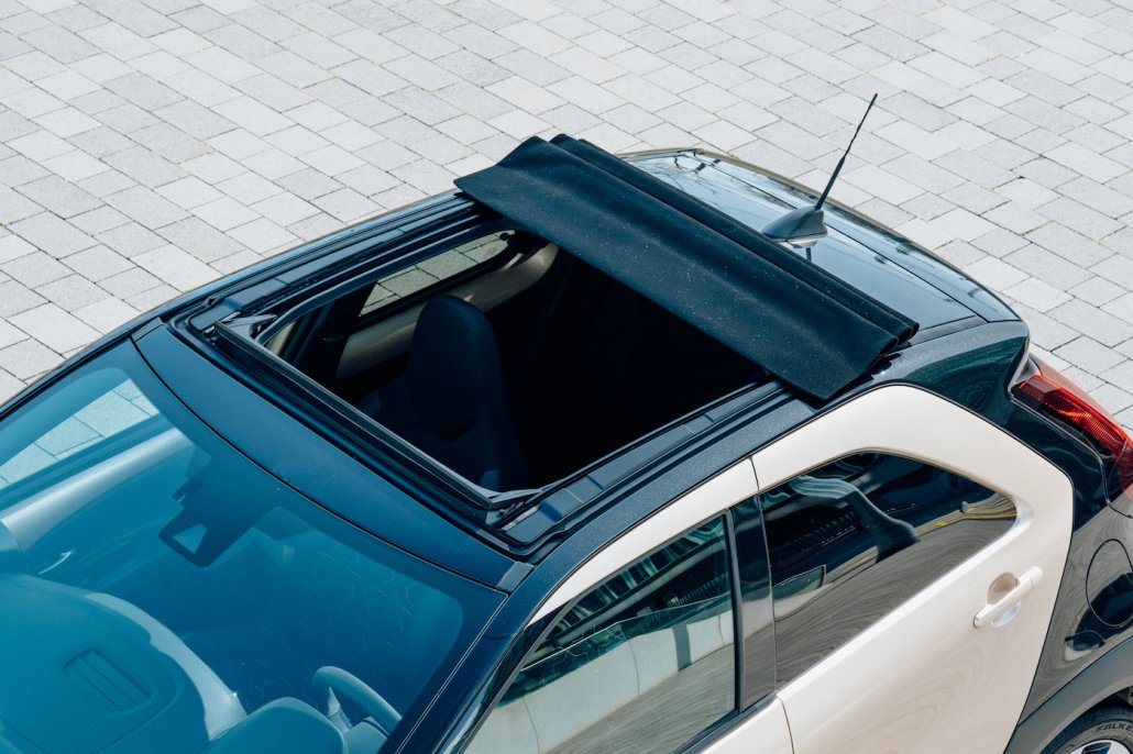 Das Faltdach eines champagnerfarben-schwarzen Toyota Aygo X ist geöfnet.