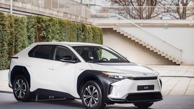 Ein weißer Toyota bZ4X steht auf einem Betonplatz. Im Hintergrund befindet sich eine Mauer, die teilweise von Pflanzen verdeckt wird.