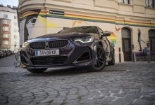 Ein BMW 2er Coupé in der Farbe Thundernight metallic steht vor einer Garageneinfahrt voller Graffiti