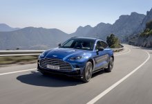 Ein blauer Aston Martin DBX 707 fährt auf einer Landstraße