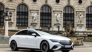 Ein weißer Mercedes EQE steht vor einem historischen Gebäude.