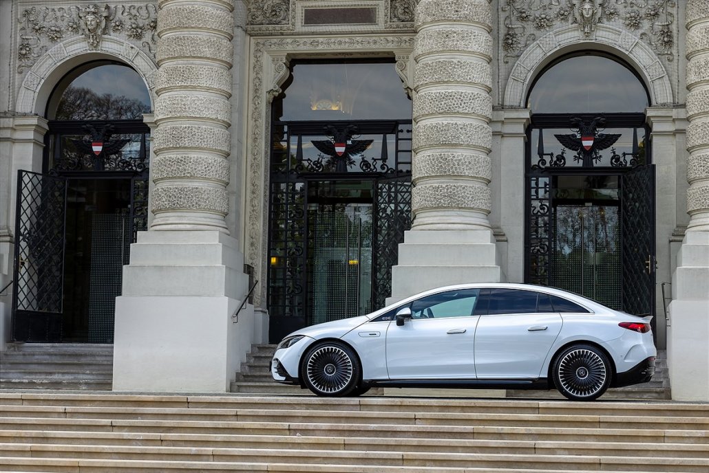 Ein weißer Mercedes EQE steht vor einem historischen Gebäude.
