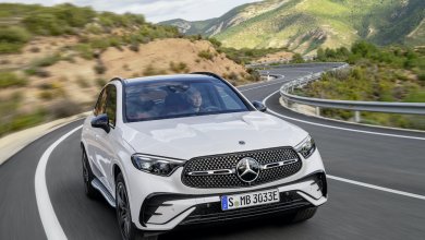 Ein weißer Mercedes GLC fährt auf einer Landstraße durch eine hügelige Landschaft