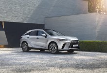 Ein silberner Lexus RX 2023 steht vor einem modernen Gebäude