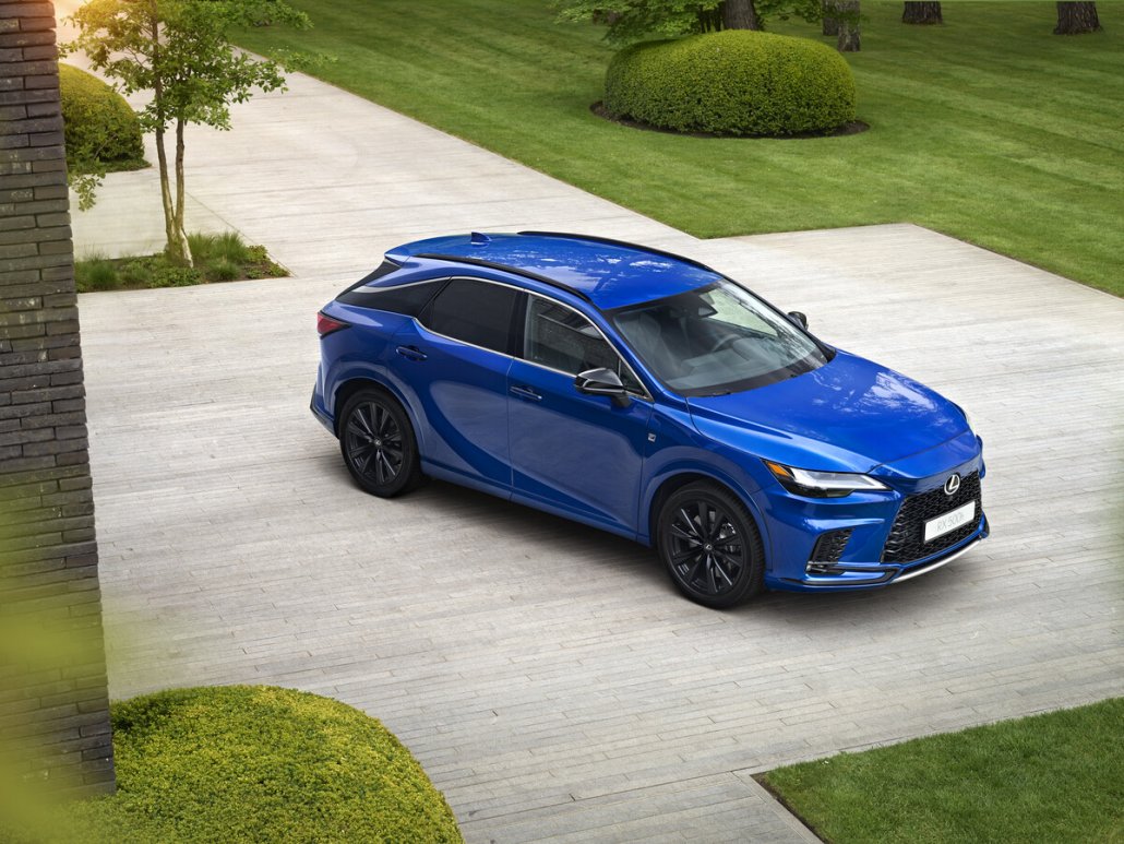 Ein blauer Lexus RX 2023 steht auf einem Parkplatz vor einem gepflegten Rasen