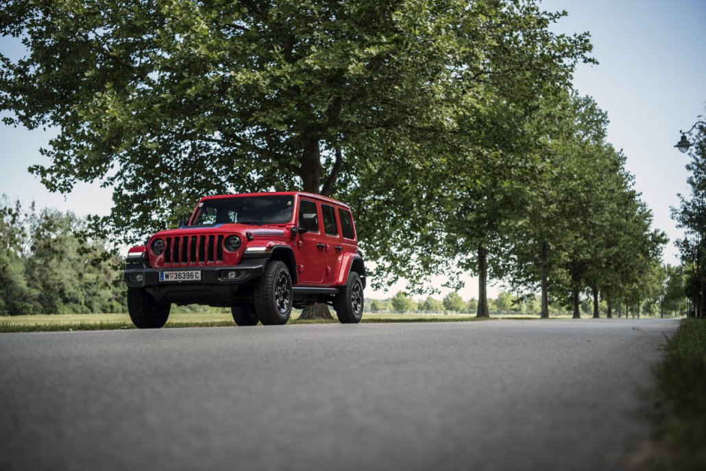 Ein roter Jeep Wrangler steht auf einer Allee