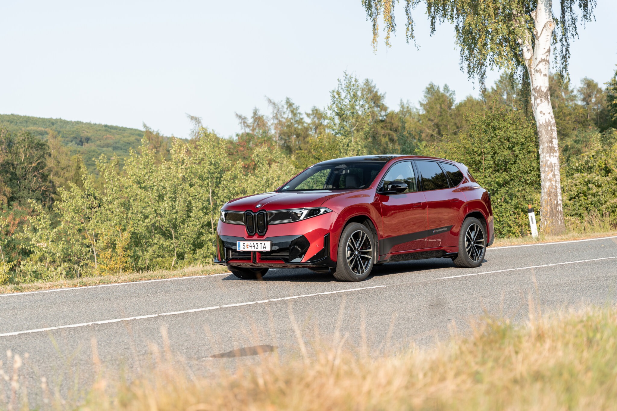 Roter BMW iX3 40 in der Frontansicht auf einer Landstraße im Wienerwald