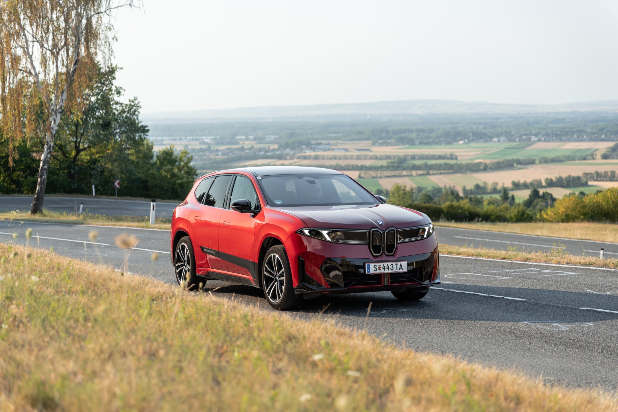 BMW iX3 40 in Rot auf einer Landstraße über dem Wiener Becken