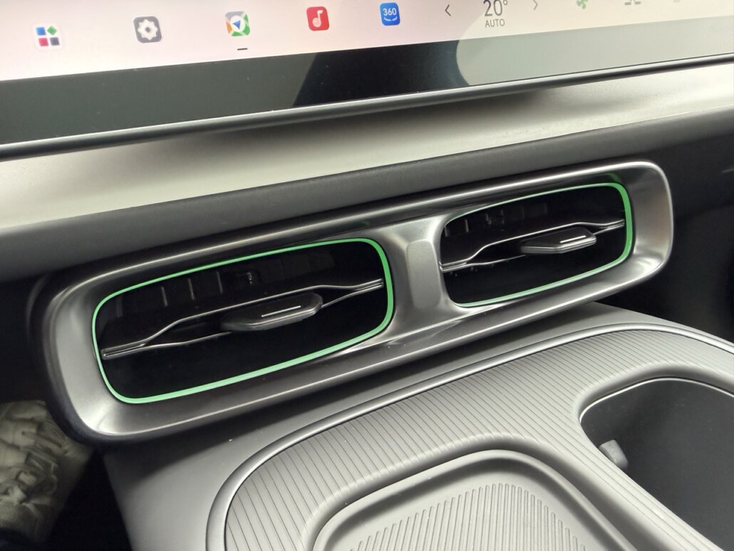 Das Bild zeigt den Innenraum eines Autos, genauer eine Detailaufnahme der Lüftungsdüsen im Armaturenbrett mit grünen Akzenten und Teilen des Touchscreens darüber.