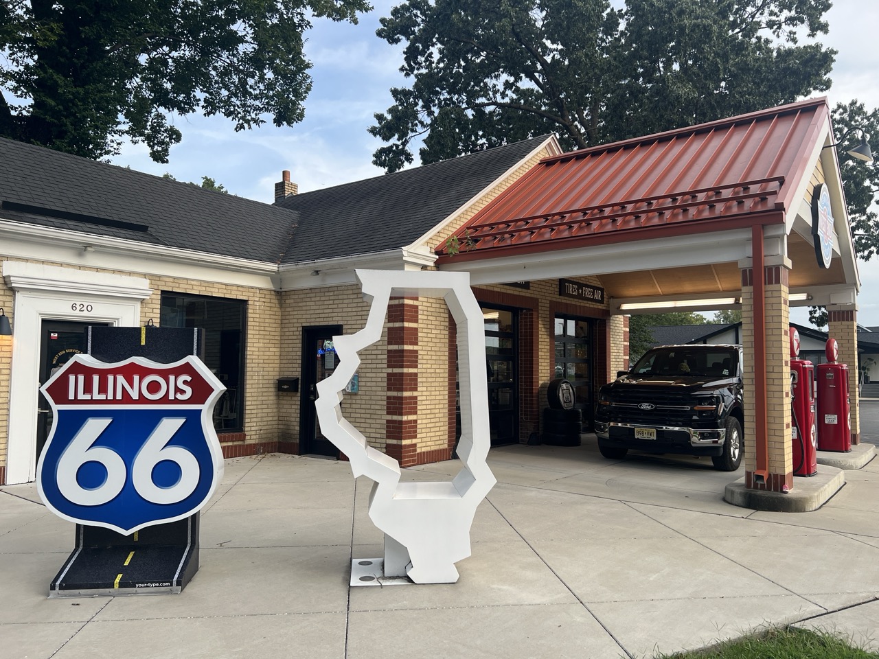 Schwarzer Ford-Pick-up unter dem Vordach einer historischen Tankstelle neben Illinois- und Route-66-Schildern