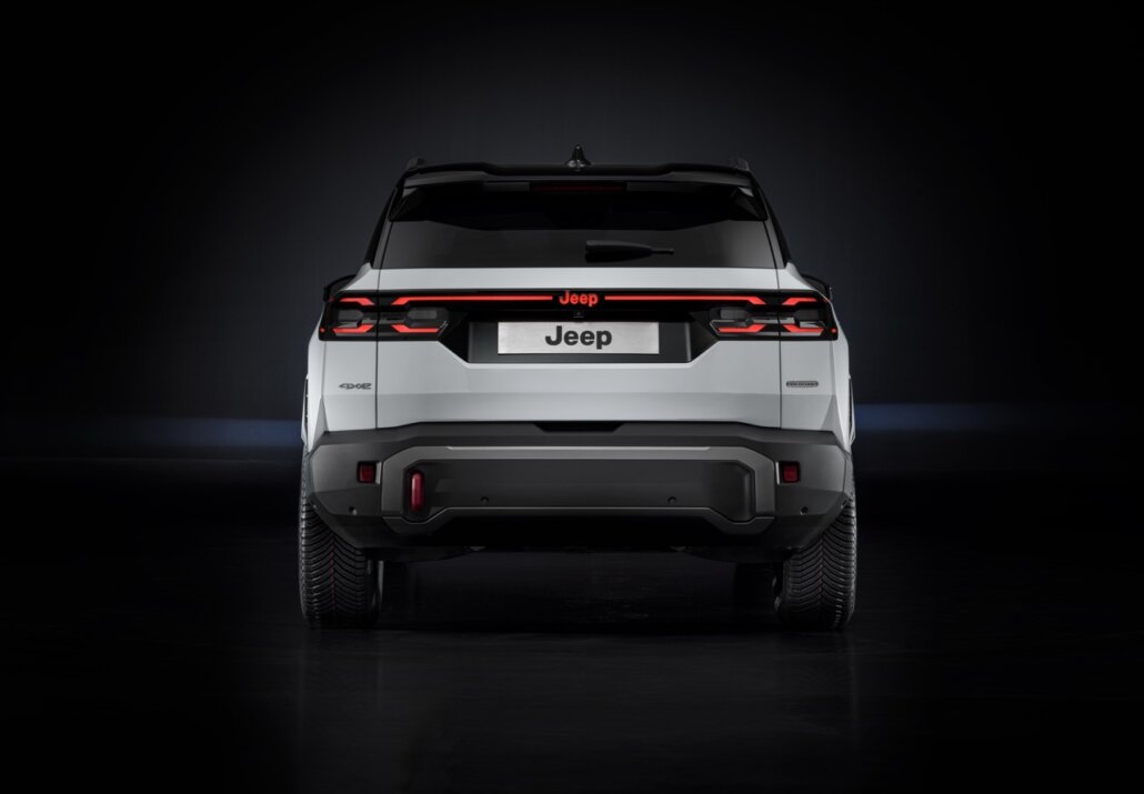 Das Foto zeigt die Heckansicht eines weißen Jeep SUV vor dunklem Hintergrund.