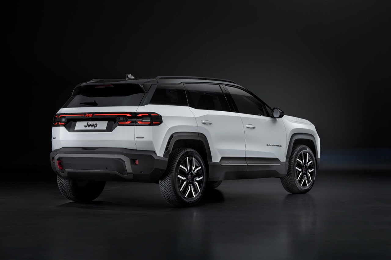 Ein weißer Jeep Compass SUV in Dreiviertelansicht von hinten rechts in einem dunklen Studio.