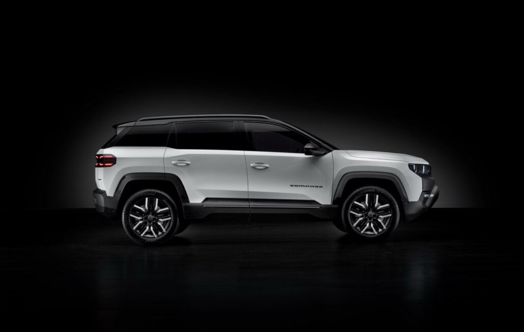 Ein weißer Jeep Compass SUV in Seitenansicht vor dunklem Hintergrund.