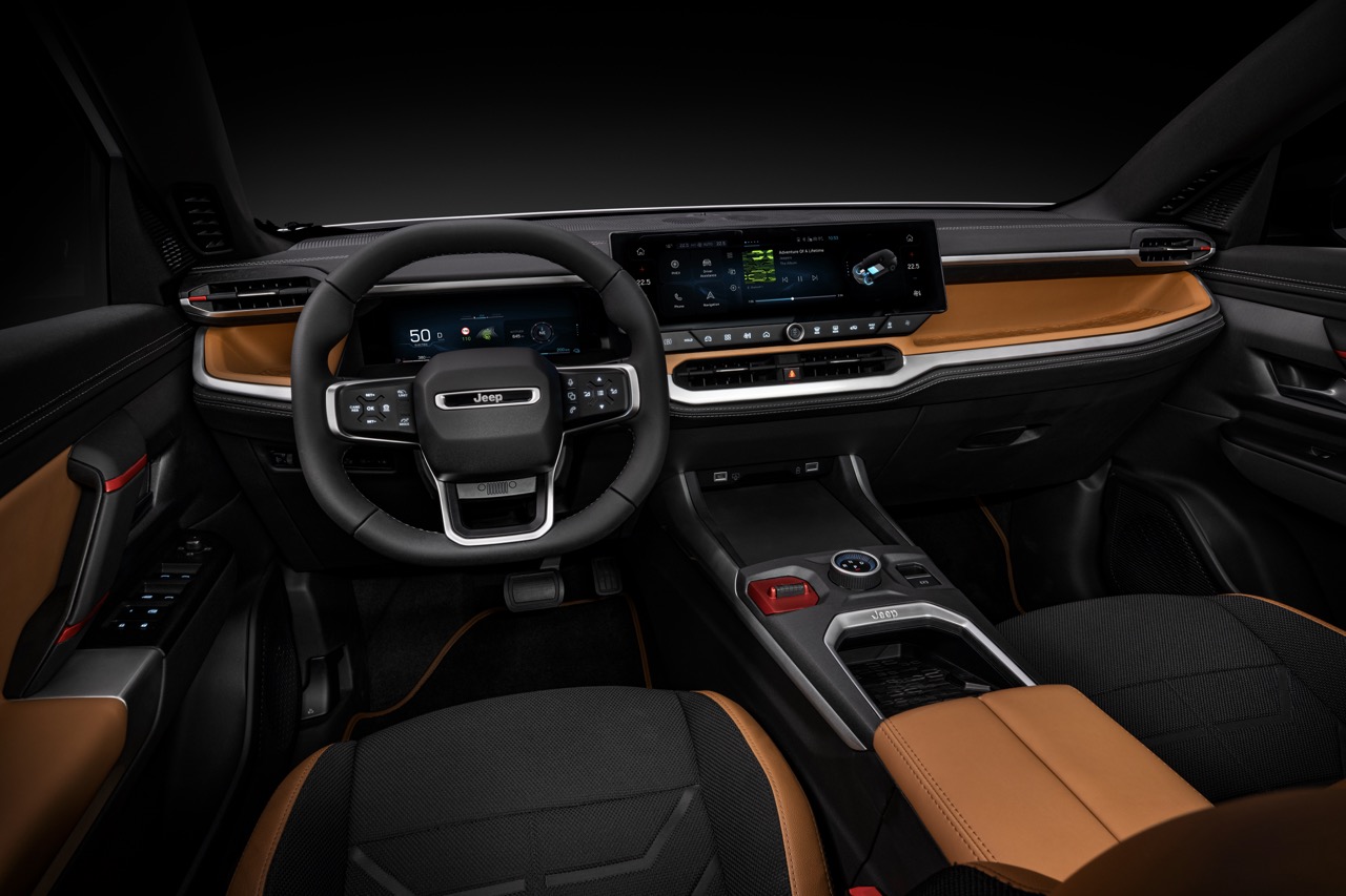 Der Innenraum eines Jeep-SUV zeigt das Armaturenbrett mit Lenkrad, Displays und schwarz-braunen Sitzen in der Totalen von vorn.