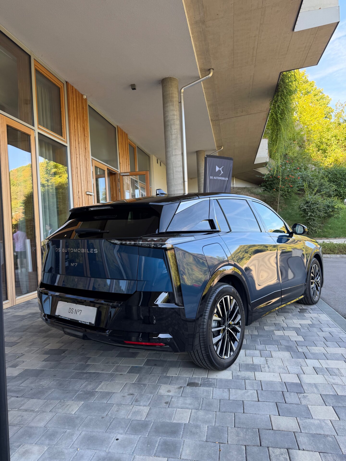DS N°7 Österreich: dunkler SUV in Dreiviertelansicht hinten vor modernem Gebäude