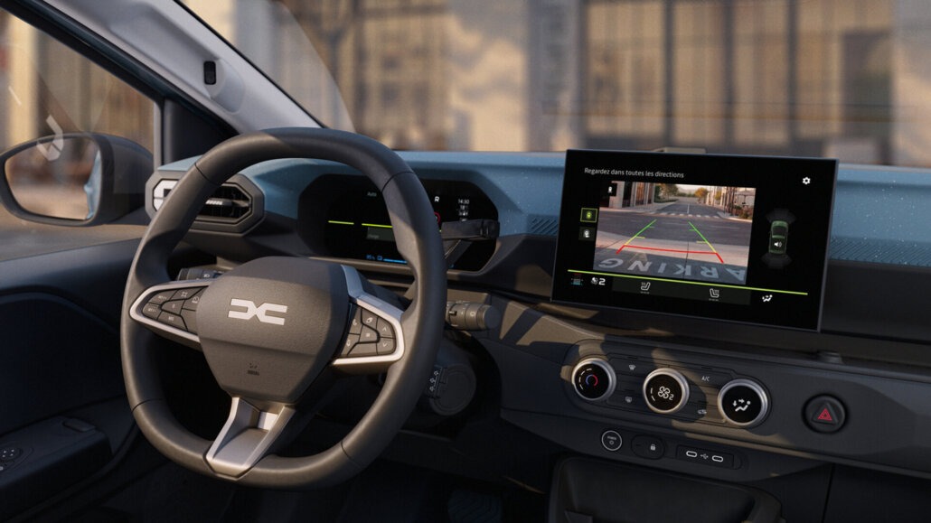 Das Foto zeigt den Innenraum eines Autos mit dem Lenkrad, dem Armaturenbrett und dem Infotainment-Bildschirm, der die Rückfahrkamera zeigt, aus der Perspektive vom Fahrersitz.
