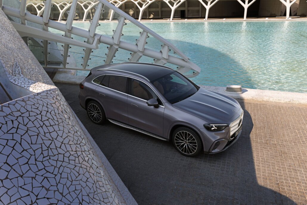 Grauer Mercedes-Benz GLC elektrisch in Dreiviertelansicht neben einem Wasserbecken und moderner Architektur