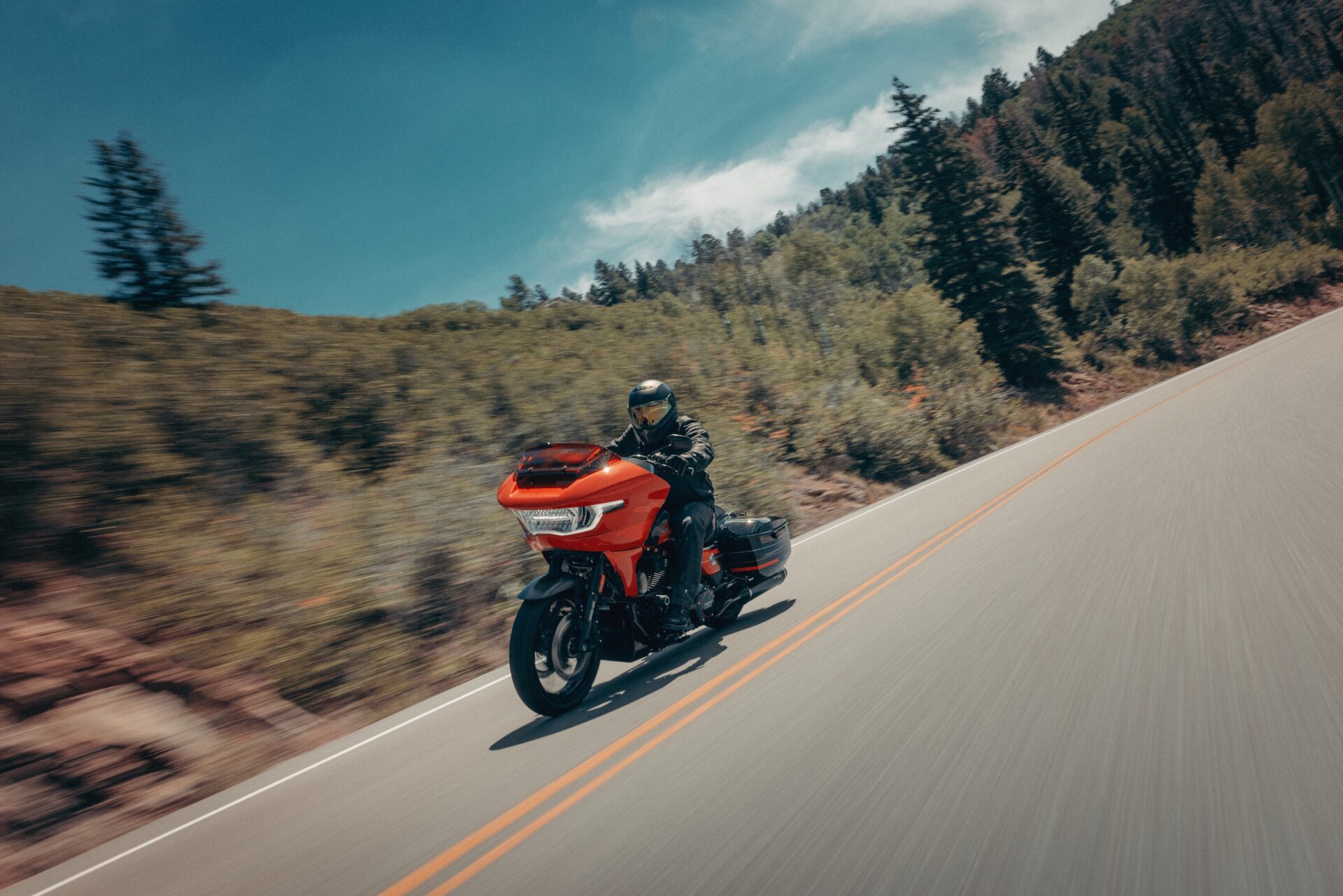 Orangefarbenes Harley-Davidson-Touring-Motorrad in Fahrt auf einer Bergstraße