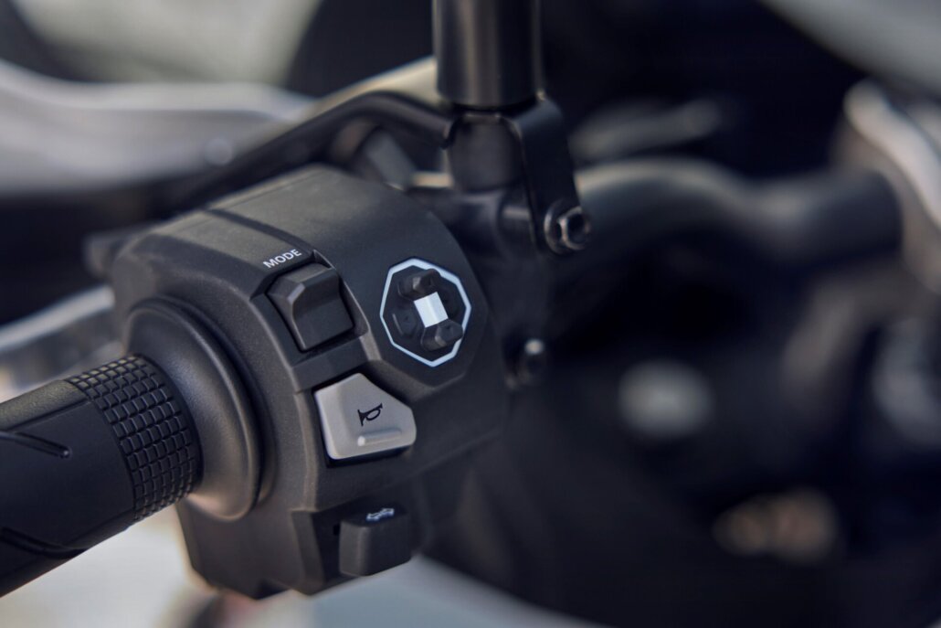 Das Bild zeigt ein Detail der schwarzen Bedieneinheit am Lenker eines Motorrads mit verschiedenen Schaltern und Tasten.