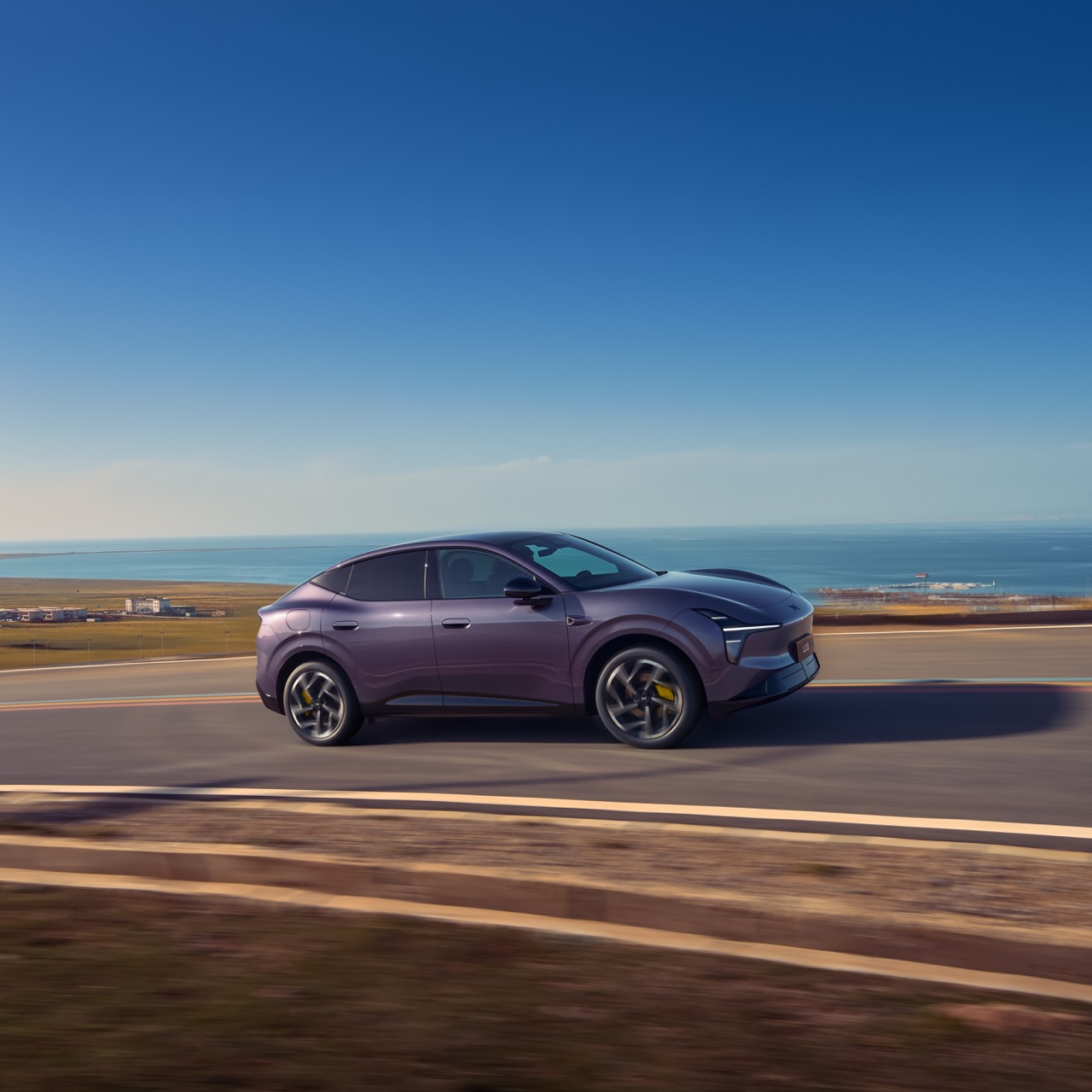 Lilafarbener Crossover-SUV auf Küstenstraße unter blauem Himmel.