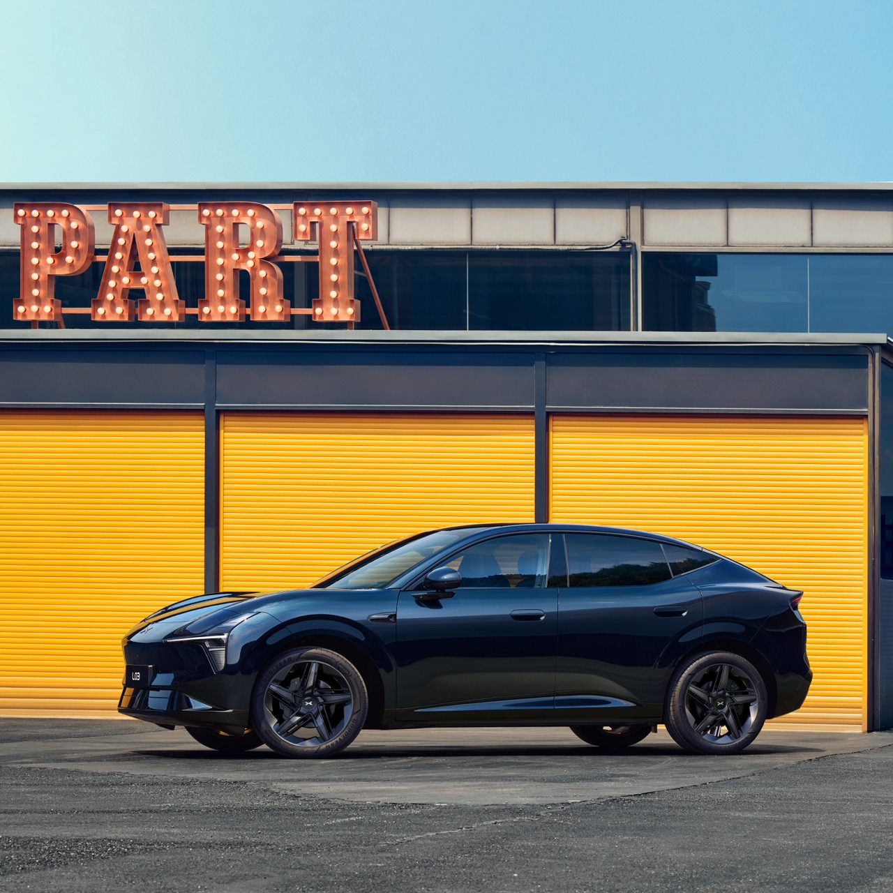 Dunkles Crossover-SUV-Coupé in Seitenansicht vor gelben Toren.